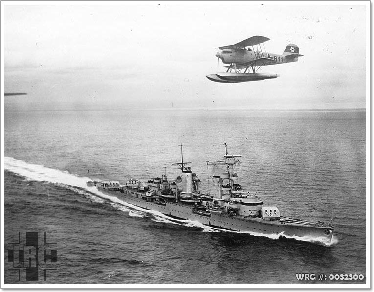 A Heinkel He 60 flies above the German light cruiser Köln