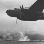B-25 Mitchell over Cape Gloucester as bombs from other bombers burst on Japanese gun positions on New Britain, 1944. WRG-0021498